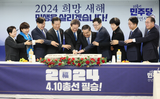 이재명 더불어민주당 대표와 홍익표 원내대표 등 참석자들이 1일 서울 여의도 중앙당사에서 열린 신년인사회에서 떡 케이크를 자르고 있다. 연합뉴스.